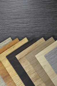 Musterstapel von Klickverschluss-Laminat, Laminatstruktur in Holz- und Steinoptik, mehrere Farben.