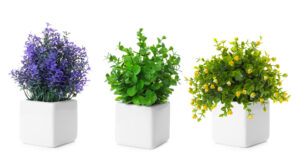 Reihe von künstlichen Pflanzen in Blumentöpfen, isoliert auf weißem Hintergrund.