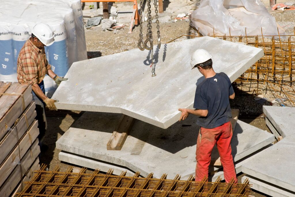 Bauarbeiter bewegen Betonplatten mit Kran