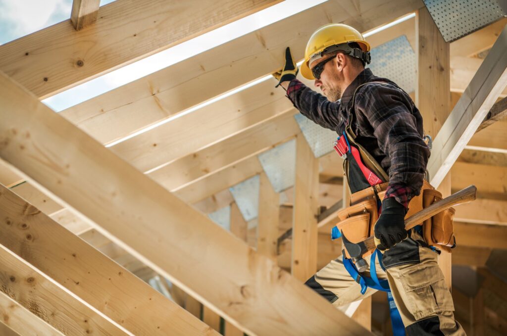 Handwerker sichert Holzbalken auf Baustelle