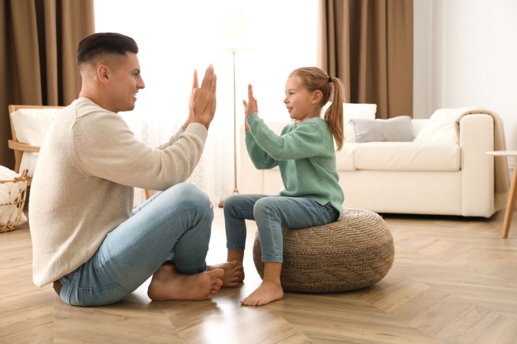 Vater und Tochter spielen barfuß auf warmem Boden mit Fußbodenheizung.