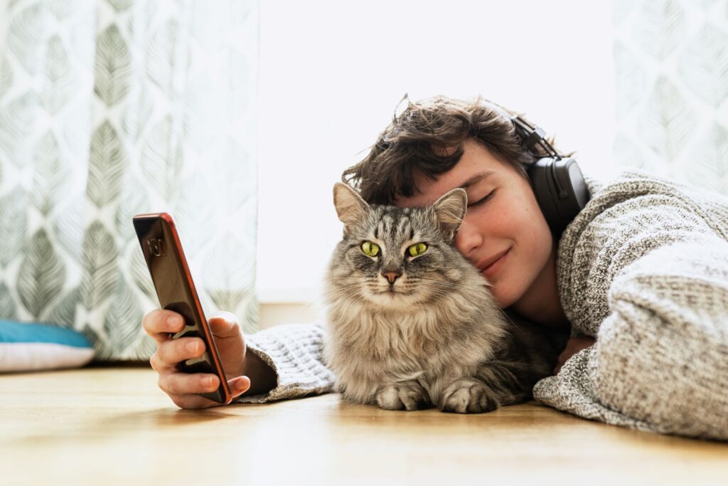 Jugendliche mit Katze genießt die warme Fußbodenheizung.