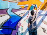 Street Art Künstler besprüht farbige Wand mit Graffiti