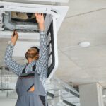 Monteur führt Wartung an Klimaanlage im Gebäude durch | elektrische Notheizung