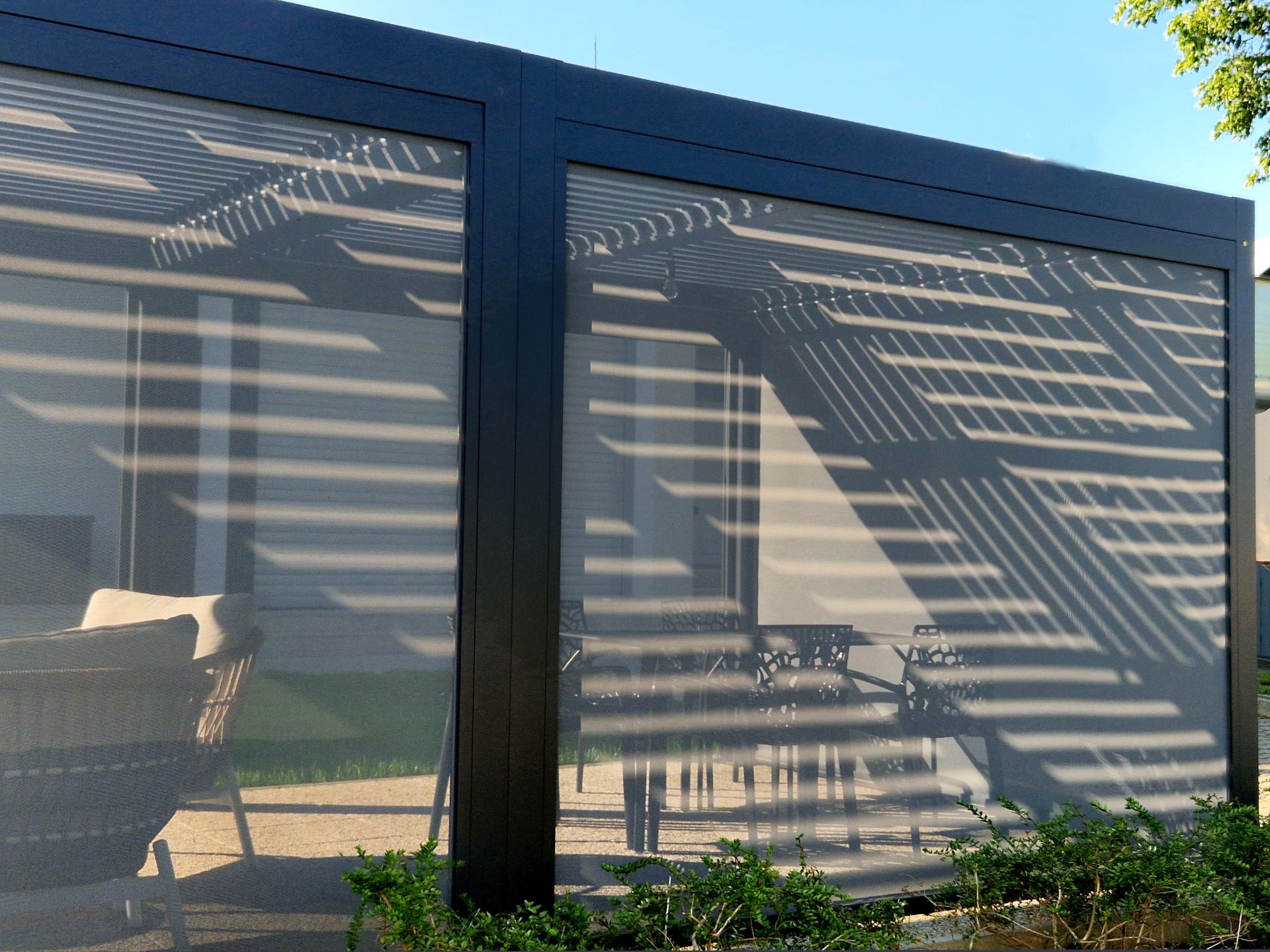 Terrassendacheindeckung mit Sonnenschutz und Lichtreflexen auf Glaslamellen